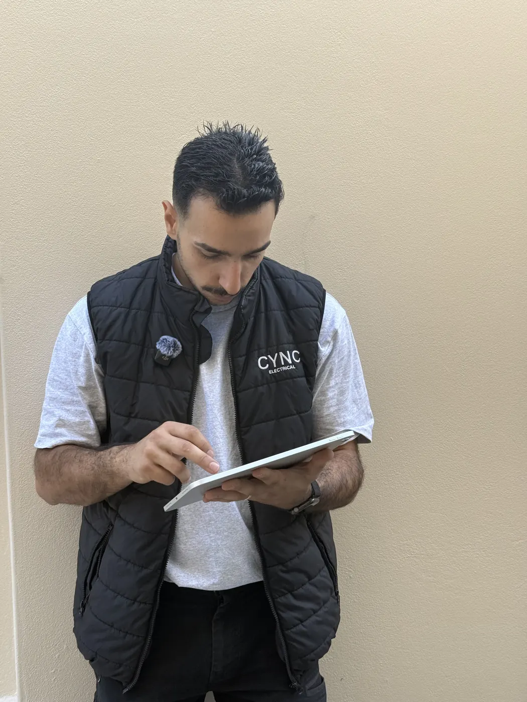 An electrician reviewing job details on a tablet on site