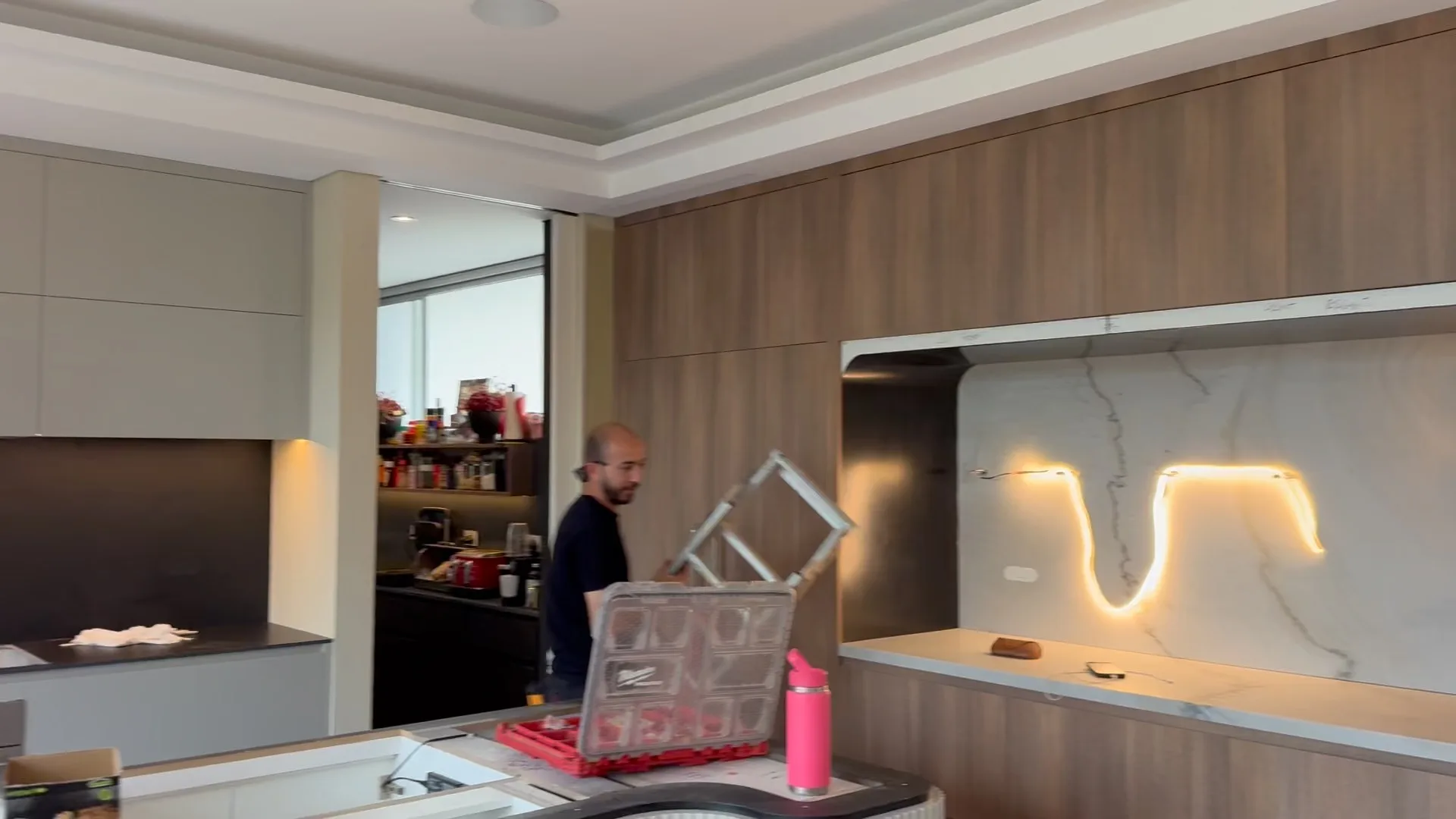 An electrician working inside a kitchen renovation, wiring a feature wall niche